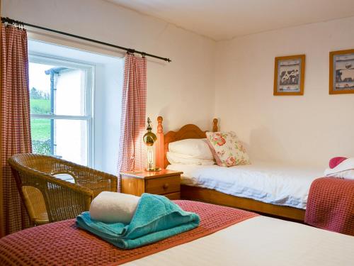 a bedroom with two beds and a window at Greenside Cottage in Caldbeck