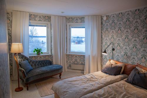 a bedroom with a bed and a chair and windows at Cozy mountain view apartment in Orrviken