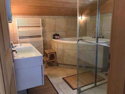 a bathroom with a shower and a sink and a tub at Gäuggeliweg 36, Klosters in Klosters