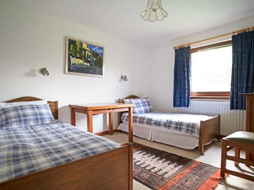 a bedroom with two beds and a desk and a window at Rosmuire in Rhu