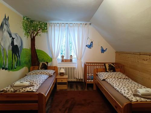 twee bedden in een kamer met een muurschildering van bomen aan de muur bij Jízdárna Malenovice in Malenovice