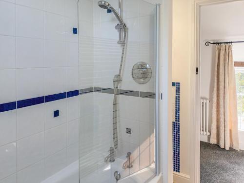 a shower with a glass door in a bathroom at Honeymead Cottage in Wick