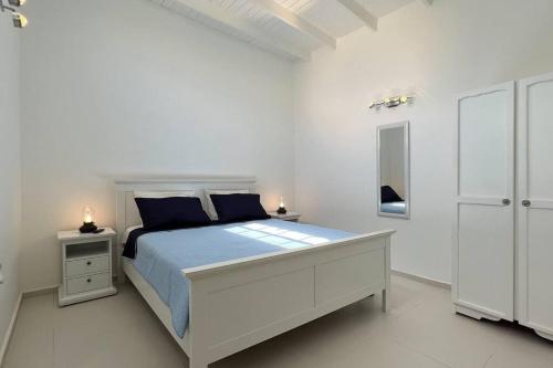 biała sypialnia z dużym łóżkiem i niebieskimi poduszkami w obiekcie Hofi Celia w mieście Blue Bay