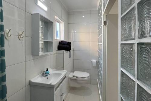 biała łazienka z toaletą i umywalką w obiekcie Hofi Celia w mieście Blue Bay