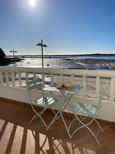 a table and chairs on a balcony with the beach at Apartamento en primera línea de playa in El Rompido