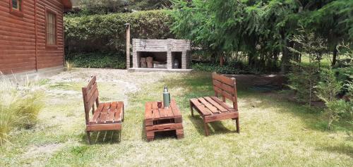 two wooden chairs and a table in a yard at Cabaña potrerillos La Tabaida in Potrerillos