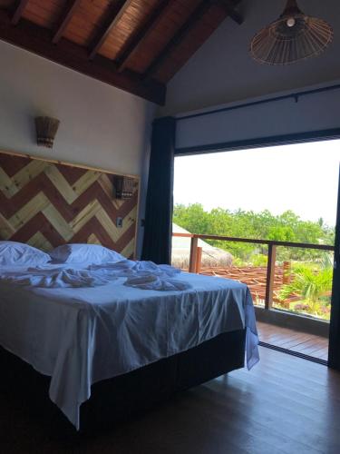 a bedroom with a bed and a large window at Barong EcoVilla in Barra Grande
