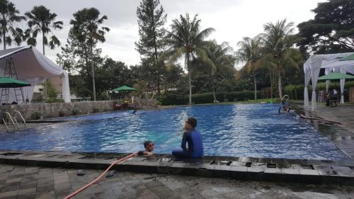 a woman and a child sitting in front of a swimming pool at Villa Bukit Nirwana in Bogor