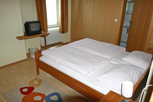 a bed in a bedroom with a tv on a table at Stiftsgasthof Hochburg in Hochburg-Ach