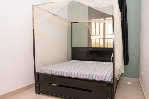 Cama con dosel en habitación con ventana en Cheerful 4-bedroom home with parking en Buyumbura