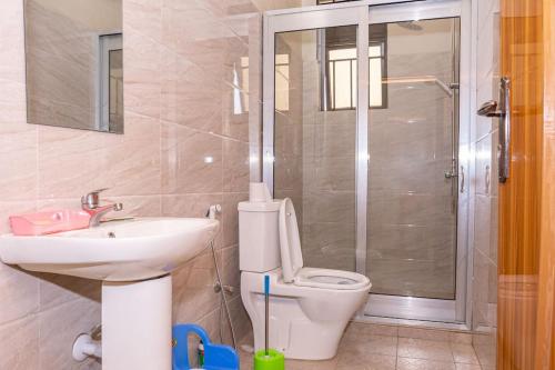 y baño con aseo, lavabo y ducha. en Cheerful 4-bedroom home with parking, en Buyumbura