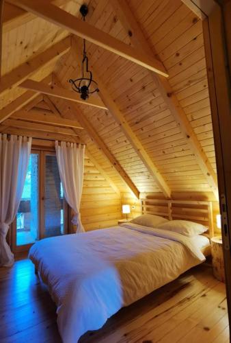 a bedroom with a large bed in a wooden ceiling at Koliba 30svibnja in Perušić