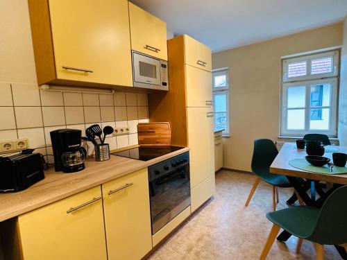 a kitchen with yellow cabinets and a table with chairs at Apartments Dombergblick - Suhl, Stadtmitte in Suhl