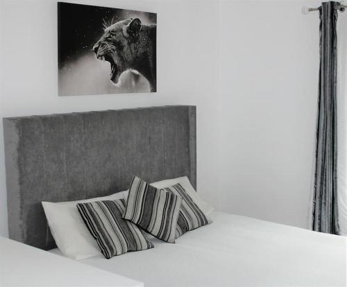 Una cama con dos almohadas y una foto de un león en Luxury Apartment Close to Town Centre, en Lexden