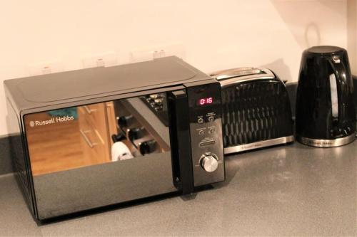 a microwave sitting on a counter next to a toaster oven at Lovely Modern Apartment Close to Town Centre in Lexden