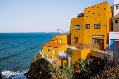 a yellow building on a cliff next to the ocean at Casanaga in Almáciga