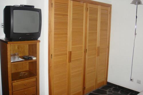 a room with a television and a wooden closet at Quarto pequeno 515 do Monte dos Arneiros in Lavre