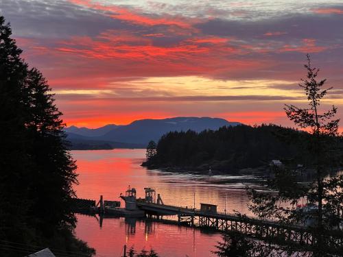 a sunset over a lake with a dock and a boat at High Point Resort in Quathiaski Cove