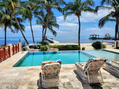 a swimming pool with two chairs and the beach at Miramar Villas Resort in San Pedro