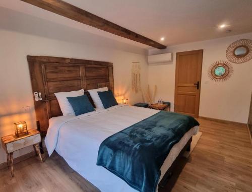 a bedroom with a large bed with a wooden headboard at La Voûte du Pilat & ces options SPA, table d'hôtes, massages in Saint-Chamond