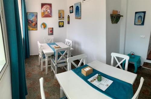 a dining room with two tables and chairs and paintings at Riad Darna in Tetouan