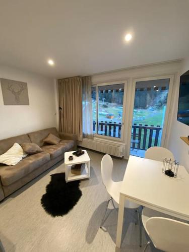 un salon avec un canapé, une table et des chaises dans l'établissement Le Lioran, La Sumène, Studio balcon tout confort aux pieds des pistes, à Laveissière