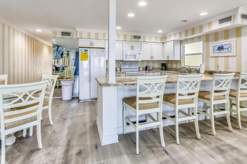 uma cozinha com armários brancos e um bar com cadeiras em Sunset Villas 1 em Clearwater Beach