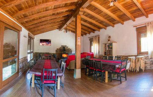 una sala de estar con techos de madera, mesas y sillas en Apartamentos Rurales El Prado, en Pinofranqueado