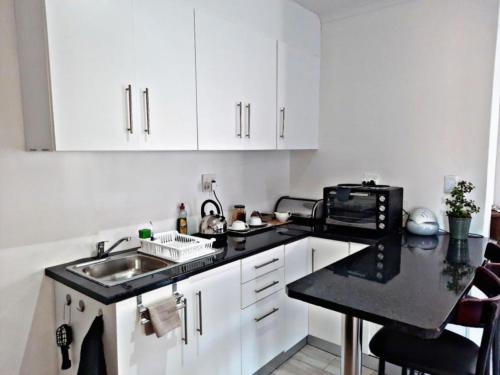 cocina blanca con fregadero y microondas en Feel@Home, en Ciudad del Cabo
