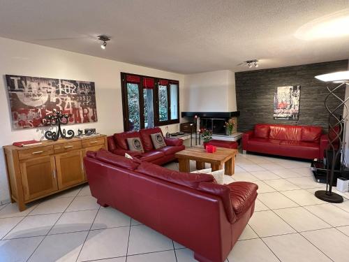 uma sala de estar com dois sofás vermelhos e uma mesa em Hadassa New York em Steffisburg
