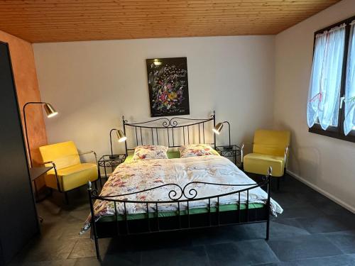 a bedroom with a bed with two yellow chairs at Hadassa New York in Steffisburg