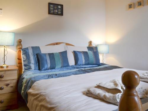 a bedroom with a bed with blue and white pillows at Low Tide in Cellardyke