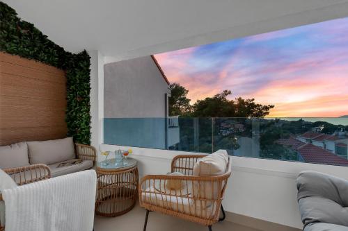 a balcony with chairs and a large window with a sunset at The Goldenhour Apartment in Makarska