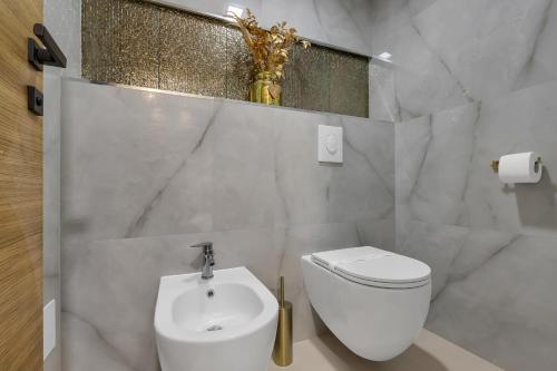 a bathroom with a white toilet and a sink at The Goldenhour Apartment in Makarska