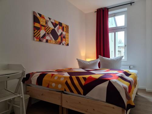 a bedroom with a bed with a colorful comforter and a window at Cityappartement am Bauhaus-Museum in Weimar