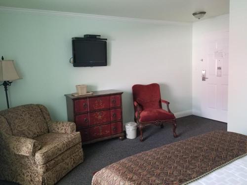 a bedroom with a bed and a chair and a tv at The City Hotel Bar & Grill in Northern Cambria