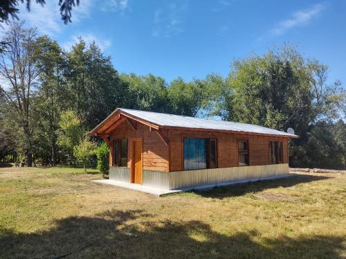 Cabaña de madera pequeña en un campo con árboles en Riberas del Azul en Lago Puelo