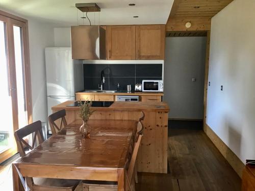 a kitchen with a wooden table and a kitchen with a refrigerator at Le Flocon - 6 personnes in Saint-Chaffrey