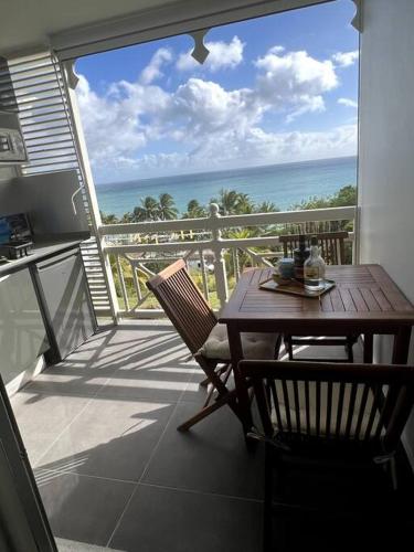 a balcony with a wooden table and chair and the ocean at The Grey Rocks Studio in Le Diamant