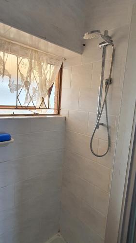 a shower with a shower head in a bathroom at Stella Maris 53 in Amanzimtoti