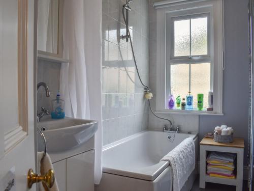 a bathroom with a tub and a sink and a window at Brookdown in Ilfracombe