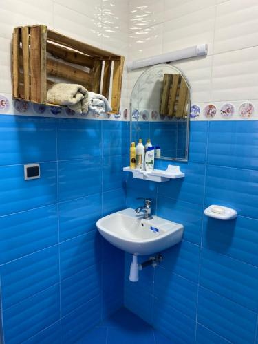 bagno blu con lavandino e specchio di Doudane Guest House Surf Morocco a Tamraght Ouzdar