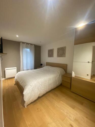 a bedroom with a large white bed and a wooden floor at Appartement duplex T3 - Paris - Roissy CDG - Parc des expositions - Disney - Astérix in Villepinte