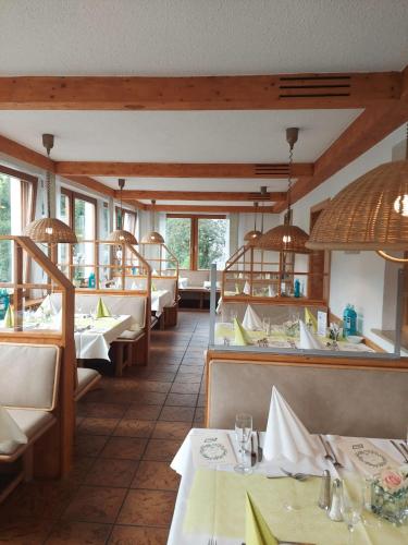 a restaurant with white tables and chairs and windows at Hotel Landgasthof Frankenstern in Gößweinstein