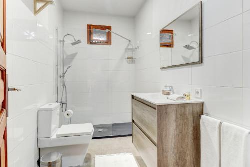 a white bathroom with a toilet and a sink at U Vila in Pollença