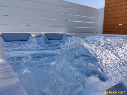 a hot tub with blue water and an umbrella at Aphrodite Luxury Apartments in Agios Prokopios