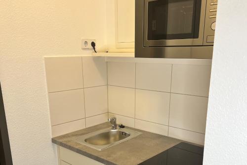 eine Küche mit einer Spüle und einer Mikrowelle in der Unterkunft SKYAPPART Merseburg in Merseburg