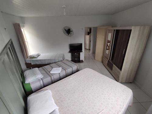 Habitación pequeña con 2 camas y TV. en Flat Três Marias, en Goiânia