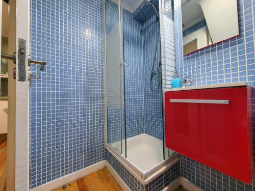 a blue tiled bathroom with a shower and a red cabinet at Casa do Garcês by Lisbon Village Apartments in Lisbon