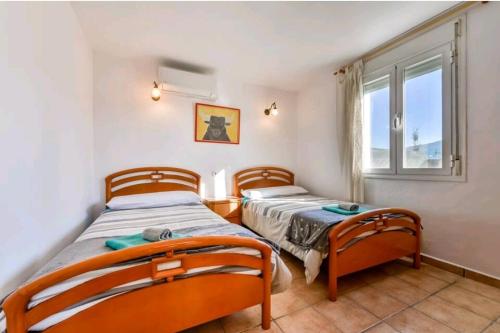 two beds in a room with a window at Casa de vacaciones con piscina comunitaria in Teulada